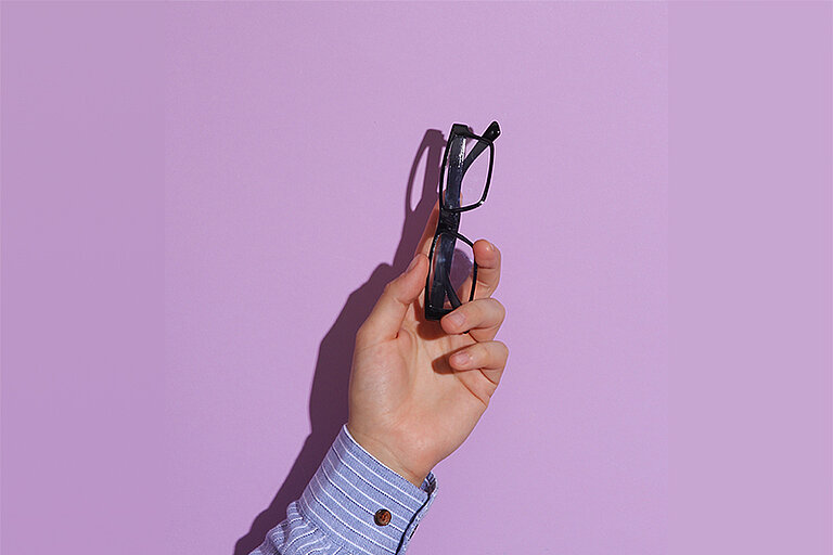 eine ausgestreckte Hand hält eine Brille
